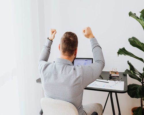 Person stretching arms upwards away from their computer desk